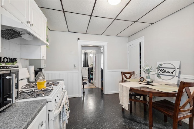 23 Auburn St, Pawtucket, RI 02860 - kitchen featuring white range with gas stovetop, wainscoting, a paneled ceiling, white cabinetry, and under cabinet range hood