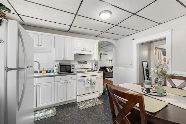 23 Auburn St, Pawtucket, RI 02860 - kitchen with white appliances, a drop ceiling, arched walkways, white cabinets, and under cabinet range hood