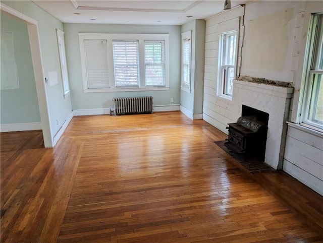 33 Zella St, Providence, RI 02908 - unfurnished living room featuring radiator heating unit, a wood stove, hardwood / wood-style flooring, and baseboards