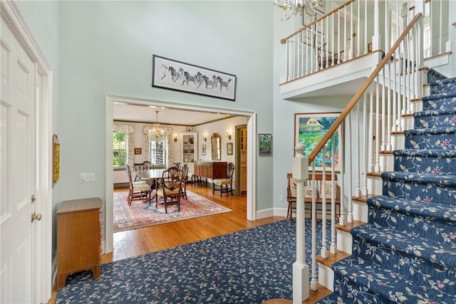 576 W Main Rd, Little Compton, RI 02837 - dining room featuring a chandelier, wood finished floors, stairs, a towering ceiling, and baseboards