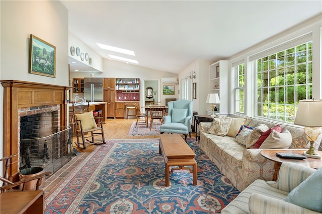 576 W Main Rd, Little Compton, RI 02837 - living room featuring lofted ceiling, a skylight, light wood-style flooring, and a brick fireplace