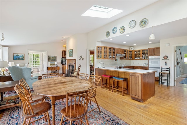 576 W Main Rd, Little Compton, RI 02837 - dining room with light wood-style flooring, lofted ceiling, a skylight, a fireplace, and recessed lighting