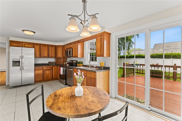 39 Exeter Blvd, Narragansett, RI 02882 - kitchen featuring appliances with stainless steel finishes, light tile patterned floors, dark countertops, a chandelier, and brown cabinets