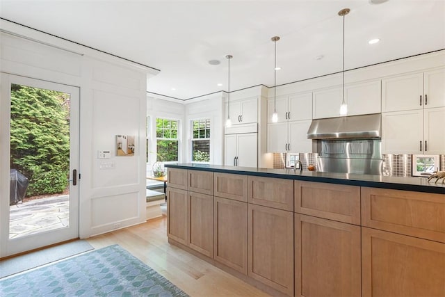 25 Walnut St, Jamestown, RI 02835 - kitchen with exhaust hood, light wood finished floors, dark countertops, and backsplash
