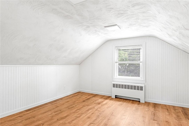 33 Upland Way, Barrington, RI 02806 - additional living space featuring radiator heating unit, wood finished floors, vaulted ceiling, and a textured ceiling