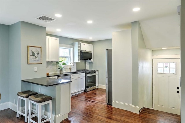 101 Knollwood Ave, Cranston, RI 02910 - kitchen with stainless steel appliances, dark countertops, a kitchen breakfast bar, a peninsula, and white cabinetry