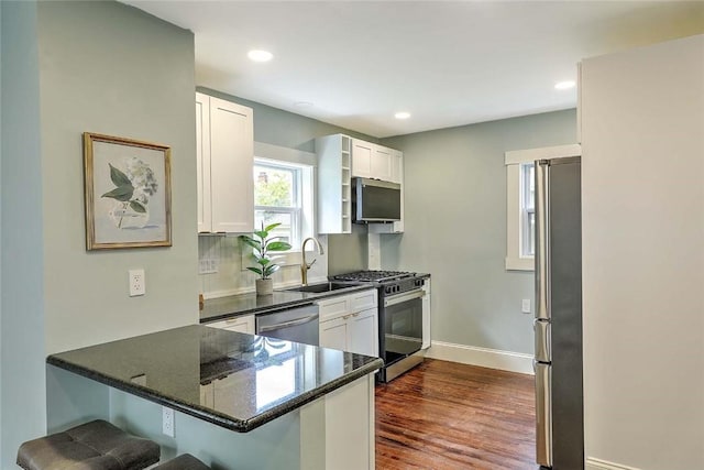 101 Knollwood Ave, Cranston, RI 02910 - kitchen with stainless steel appliances, a sink, a peninsula, a breakfast bar area, and dark wood finished floors