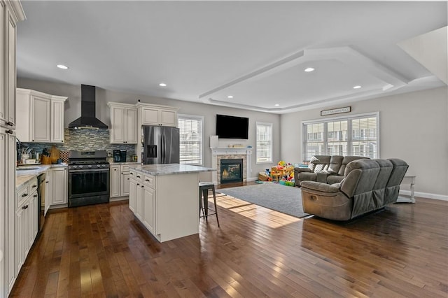 132 Theresa Marie Ave, Woonsocket, RI 02895 - kitchen with stainless steel appliances, wall chimney exhaust hood, open floor plan, a breakfast bar, and dark wood-style flooring