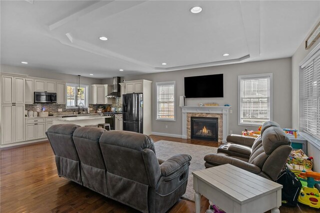 132 Theresa Marie Ave, Woonsocket, RI 02895 - living area with a tray ceiling, wood finished floors, recessed lighting, a lit fireplace, and baseboards