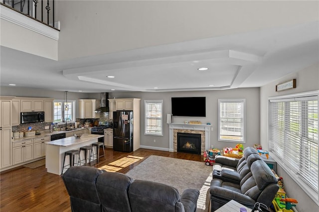 132 Theresa Marie Ave, Woonsocket, RI 02895 - living area featuring dark wood-style floors, a lit fireplace, a tray ceiling, and recessed lighting