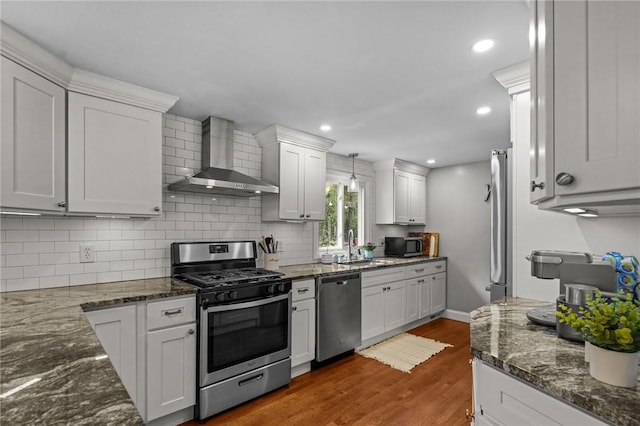 10 Bigelow Rd, Johnston, RI 02919 - kitchen with appliances with stainless steel finishes, wall chimney range hood, backsplash, dark wood-style flooring, and white cabinetry