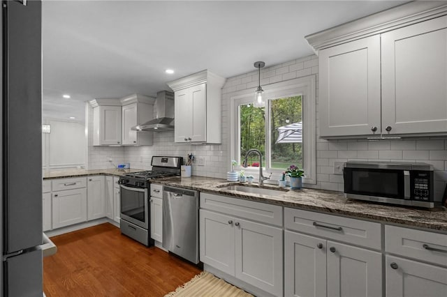 10 Bigelow Rd, Johnston, RI 02919 - kitchen featuring appliances with stainless steel finishes, wall chimney range hood, a sink, tasteful backsplash, and wood finished floors