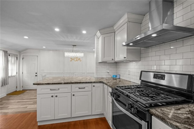 10 Bigelow Rd, Johnston, RI 02919 - kitchen featuring wall chimney range hood, gas stove, a peninsula, a chandelier, and wood finished floors