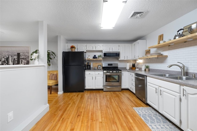 5390 Post Rd Unit 9, Warwick, RI 02818 - kitchen with appliances with stainless steel finishes, open shelves, a sink, tasteful backsplash, and a textured ceiling