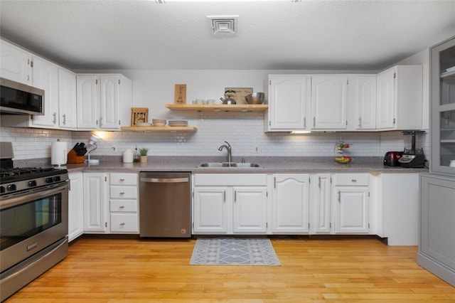 5390 Post Rd Unit 9, Warwick, RI 02818 - kitchen featuring appliances with stainless steel finishes, a sink, white cabinets, light wood-style flooring, and a textured ceiling