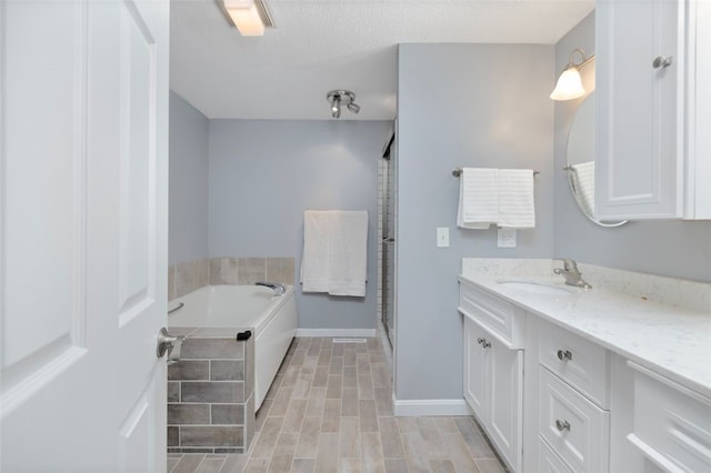 5390 Post Rd Unit 9, Warwick, RI 02818 - full bathroom with vanity, a garden tub, a shower stall, a textured ceiling, and baseboards