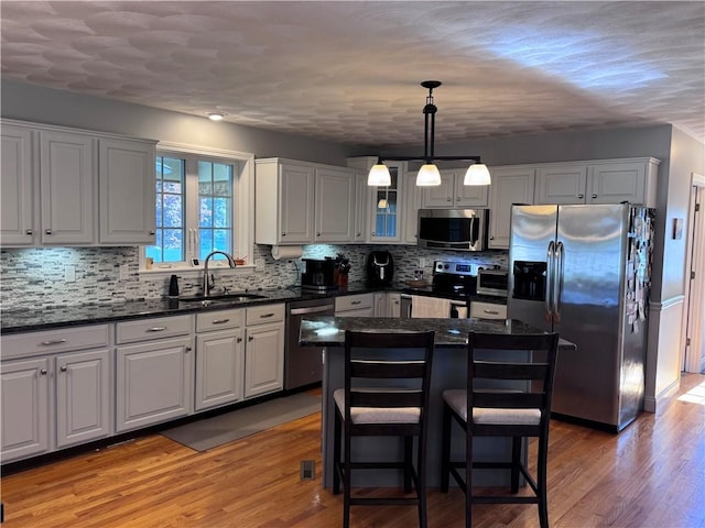 60 Farm Dr, Cumberland, RI 02864 - kitchen featuring stainless steel appliances, tasteful backsplash, glass insert cabinets, light wood-style flooring, and a kitchen island