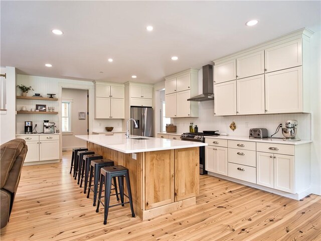 1 Hinter Way, Little Compton, RI 02837 - kitchen with wall chimney exhaust hood, appliances with stainless steel finishes, light wood-type flooring, a breakfast bar area, and tasteful backsplash