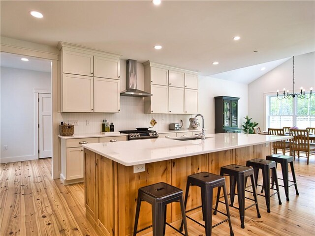1 Hinter Way, Little Compton, RI 02837 - kitchen with wall chimney exhaust hood, a sink, stainless steel stove, light wood-style flooring, and vaulted ceiling