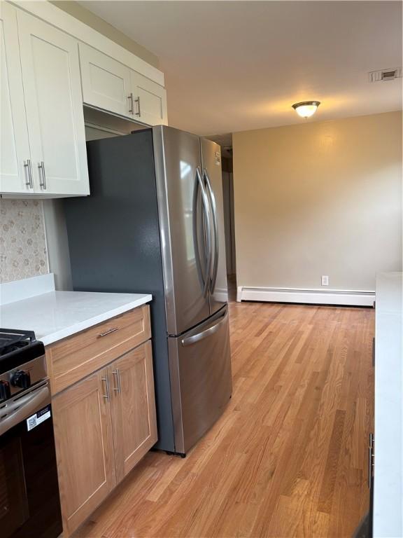 173 Martin St, East Providence, RI 02914 - kitchen featuring baseboard heating, stainless steel appliances, light countertops, and light wood-type flooring