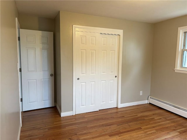173 Martin St, East Providence, RI 02914 - unfurnished bedroom with wood finished floors, baseboards, a baseboard radiator, and a closet