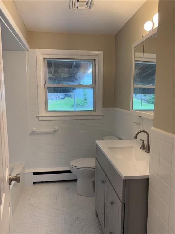173 Martin St, East Providence, RI 02914 - bathroom featuring baseboard heating, vanity, tile walls, healthy amount of natural light, and toilet
