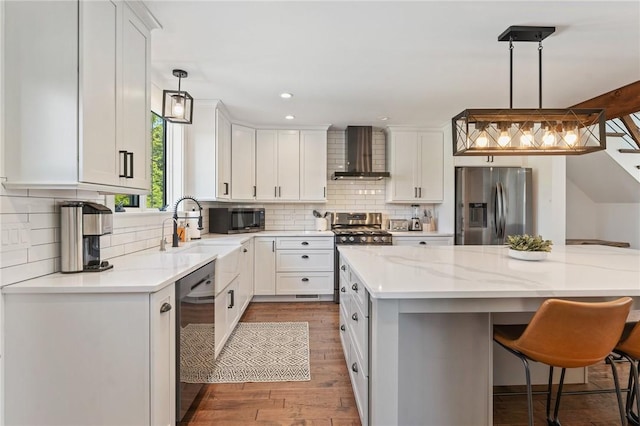 23 Hemlock St, Narragansett, RI 02882 - kitchen featuring stainless steel appliances, wall chimney range hood, wood finished floors, a breakfast bar, and a sink