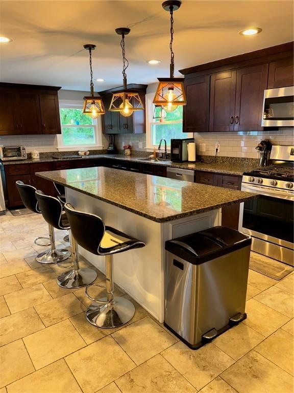 21 Baldwin Rd, Warwick, RI 02886 - kitchen featuring appliances with stainless steel finishes, a breakfast bar area, tasteful backsplash, a sink, and a kitchen island