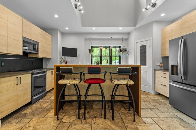 45 Lloyd Bowen Ct, Glocester, RI 02814 - kitchen with appliances with stainless steel finishes, light brown cabinetry, a kitchen bar, stone tile floors, and modern cabinets