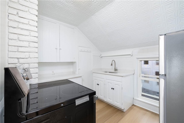 130 Hunts Ave, Pawtucket, RI 02861 - kitchen featuring freestanding refrigerator, a sink, light wood-style floors, vaulted ceiling, and white cabinetry