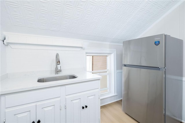 130 Hunts Ave, Pawtucket, RI 02861 - kitchen with freestanding refrigerator, a sink, white cabinets, light countertops, and light wood finished floors