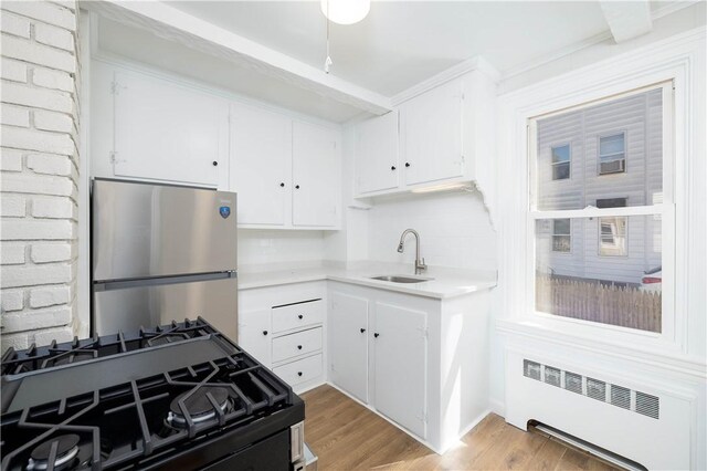 130 Hunts Ave, Pawtucket, RI 02861 - kitchen featuring freestanding refrigerator, radiator, a sink, gas stove, and white cabinets
