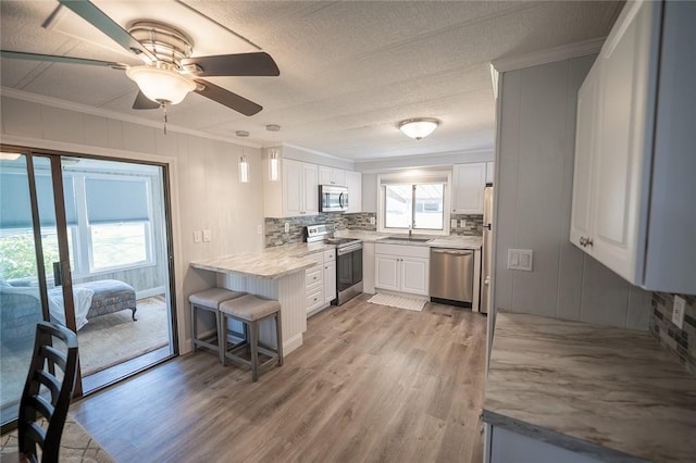 7 Lane D Dr, Coventry, RI 02816 - kitchen with stainless steel appliances, crown molding, backsplash, light wood finished floors, and ceiling fan