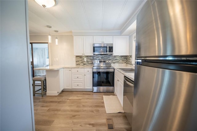7 Lane D Dr, Coventry, RI 02816 - kitchen featuring appliances with stainless steel finishes, crown molding, a peninsula, white cabinetry, and light countertops