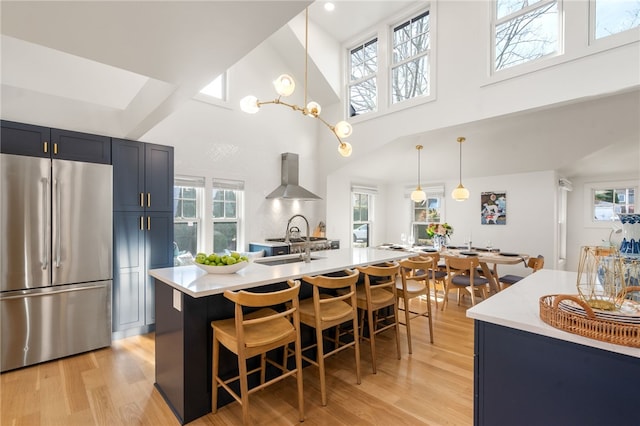 14 Robinson St, Narragansett, RI 02882 - kitchen featuring stainless steel fridge, wall chimney range hood, light countertops, light wood finished floors, and a towering ceiling