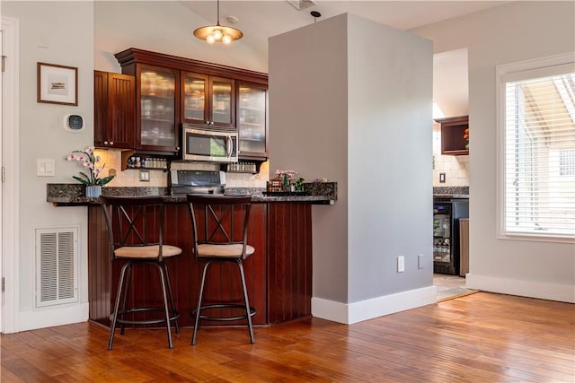 3976 Post Rd, Warwick, RI 02886 - bar area with stainless steel microwave, tasteful backsplash, wood finished floors, stove, and baseboards