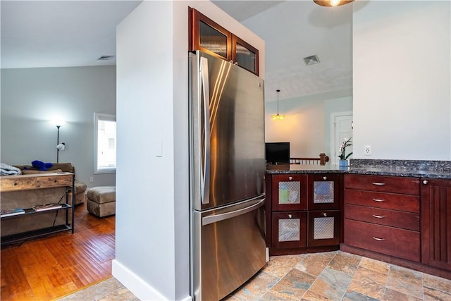 3976 Post Rd, Warwick, RI 02886 - kitchen with freestanding refrigerator, reddish brown cabinets, glass insert cabinets, dark stone countertops, and open floor plan