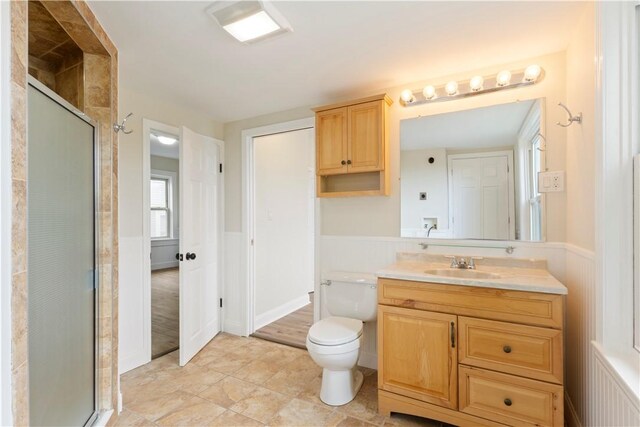 9 Woodbine St, Providence, RI 02906 - bathroom with vanity, toilet, a stall shower, wainscoting, and tile patterned flooring