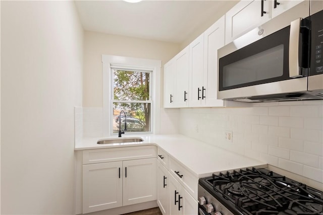 9 Woodbine St, Providence, RI 02906 - kitchen featuring appliances with stainless steel finishes, a sink, tasteful backsplash, and white cabinets
