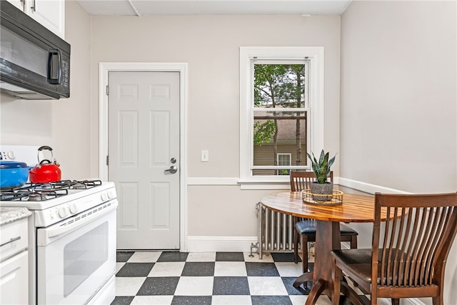 165 Wentworth Ave Unit 2E, Cranston, RI 02905 - kitchen featuring black microwave, white range with gas stovetop, dark flooring, white cabinetry, and light countertops