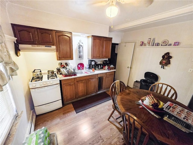106 Baxter St, Pawtucket, RI 02861 - kitchen with white range with gas stovetop, under cabinet range hood, light countertops, light wood-style flooring, and a sink