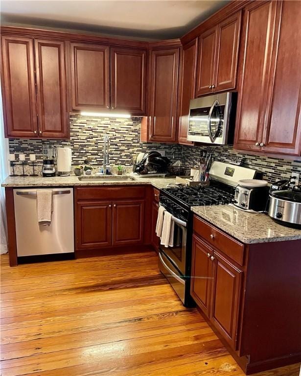 86 Edgemere Ave, Providence, RI 02909 - kitchen featuring appliances with stainless steel finishes, a sink, light wood-type flooring, tasteful backsplash, and light stone countertops