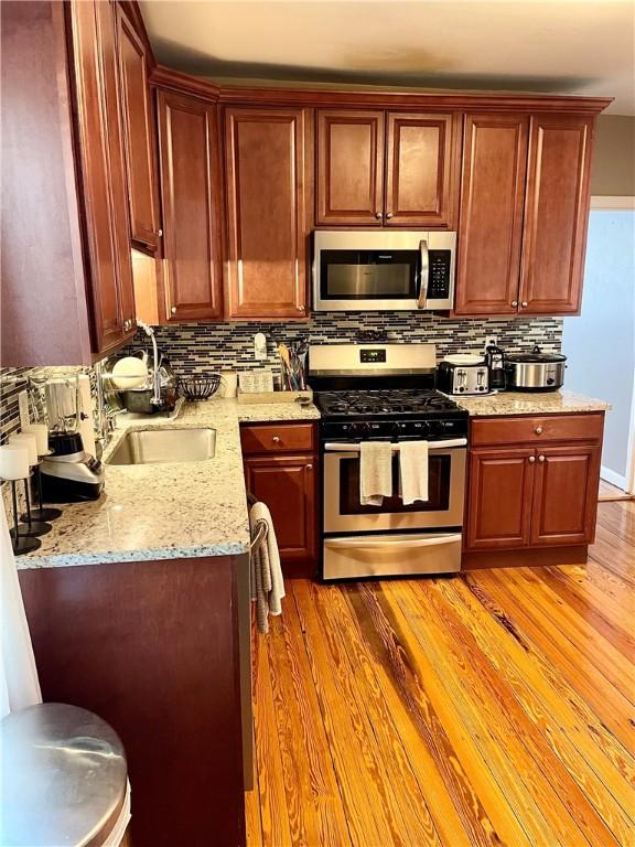 86 Edgemere Ave, Providence, RI 02909 - kitchen with appliances with stainless steel finishes, a sink, light wood finished floors, backsplash, and light stone countertops