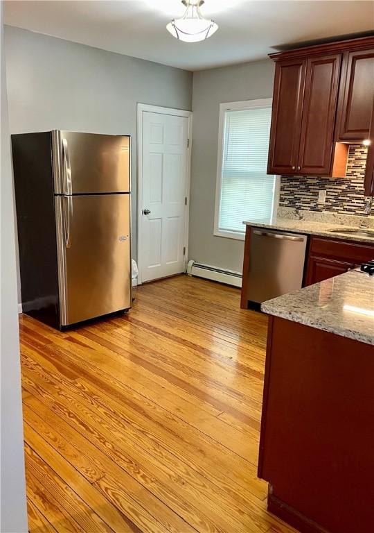 86 Edgemere Ave, Providence, RI 02909 - kitchen with stainless steel appliances, baseboard heating, a sink, light wood-style flooring, and decorative backsplash