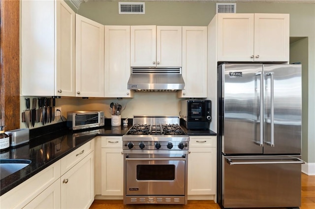 423 Hope St Unit C, Bristol, RI 02809 - kitchen featuring high end appliances, under cabinet range hood, white cabinets, and dark stone counters
