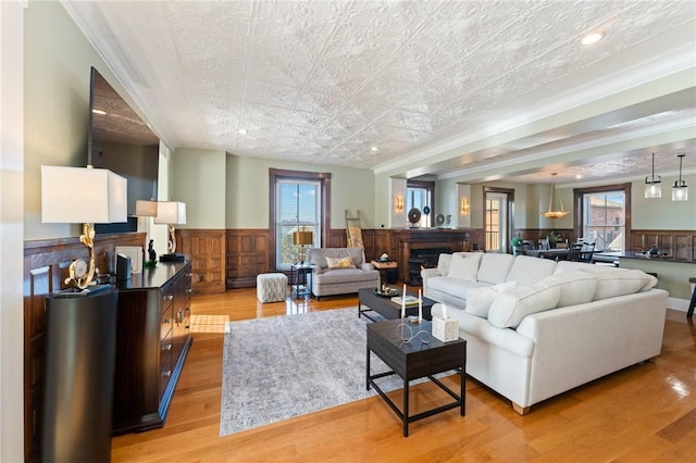 423 Hope St Unit C, Bristol, RI 02809 - living room featuring a warm lit fireplace, wainscoting, light wood-type flooring, baseboard heating, and an ornate ceiling