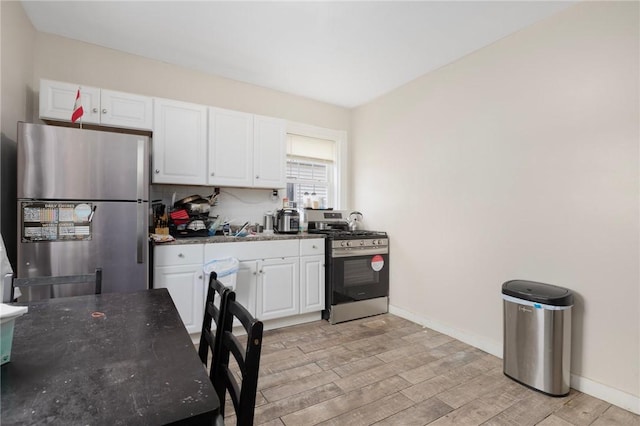 9 Sackett St, Providence, RI 02907 - kitchen featuring appliances with stainless steel finishes, white cabinets, light wood-style flooring, dark stone countertops, and baseboards
