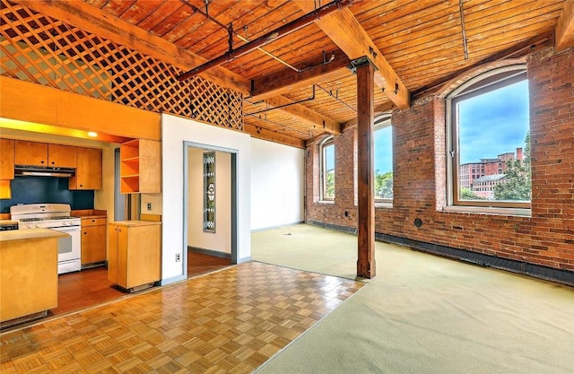 116 Chestnut St Unit G, Providence, RI 02903 - kitchen with white gas range oven, brick wall, under cabinet range hood, wooden ceiling with exposed beams, and baseboards