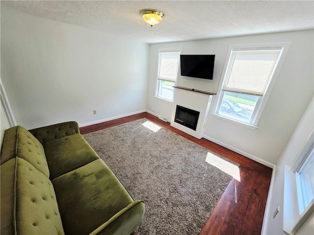 5 Rosemont Ter, North Providence, RI 02911 - unfurnished living room featuring wood finished floors, a textured ceiling, baseboards, and a glass covered fireplace