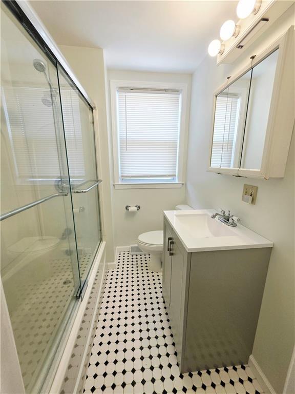 5 Rosemont Ter, North Providence, RI 02911 - bathroom featuring toilet, vanity, a shower with shower door, baseboards, and tile patterned flooring